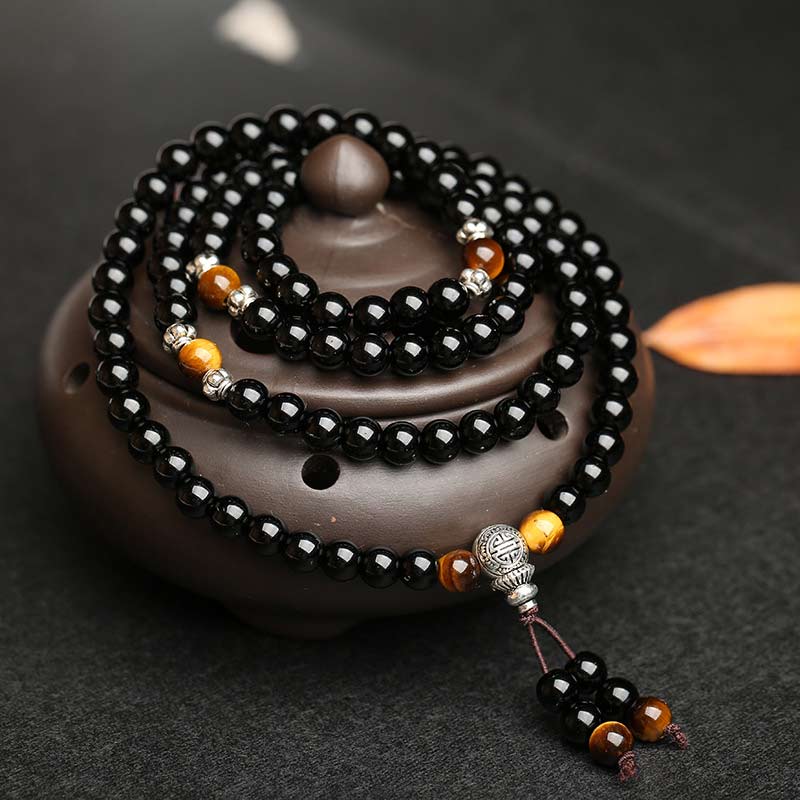 Black beaded bracelet with orange accents on a dark surface