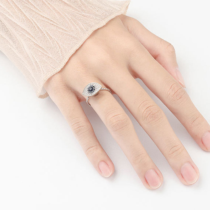 Hand wearing a silver ring with a blue gemstone on a white background