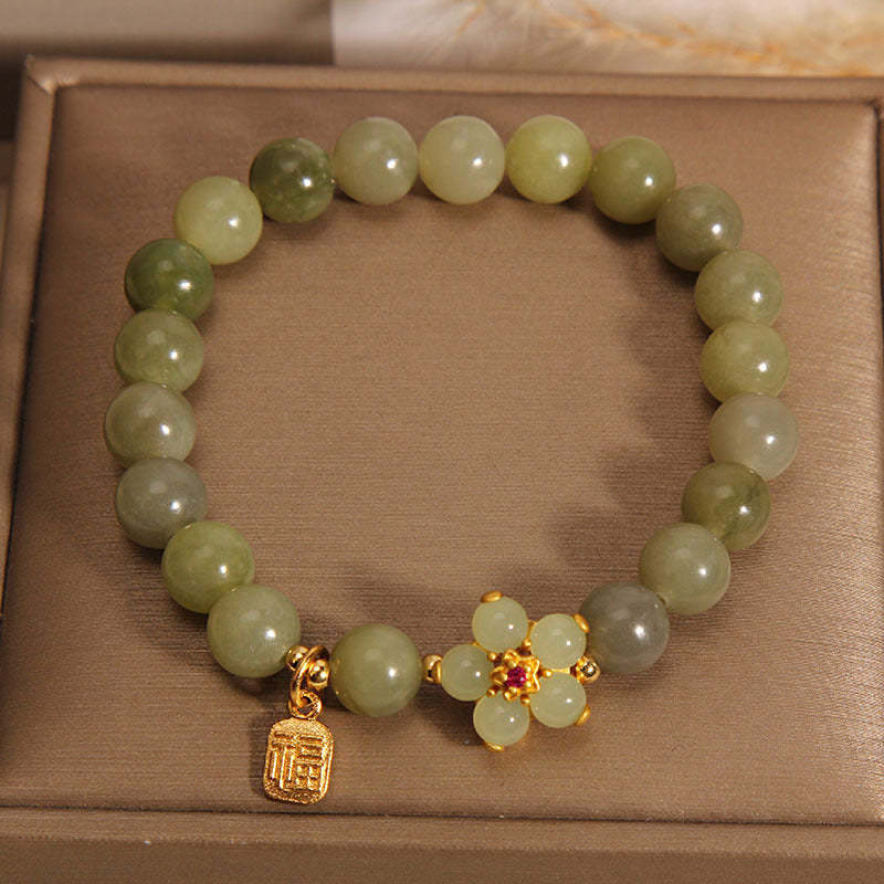 Green beaded bracelet with a gold charm on a brown surface