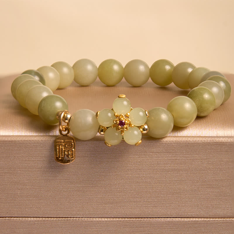 Green beaded bracelet with gold clasp and charm on a wooden surface