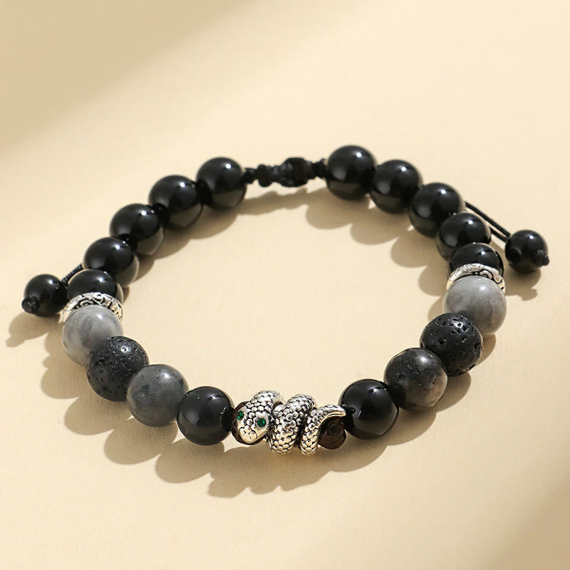Black and gray beaded bracelet with a silver charm on a beige background