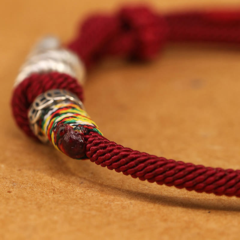 Close-up of a red cord with a colorful bead on a brown surface