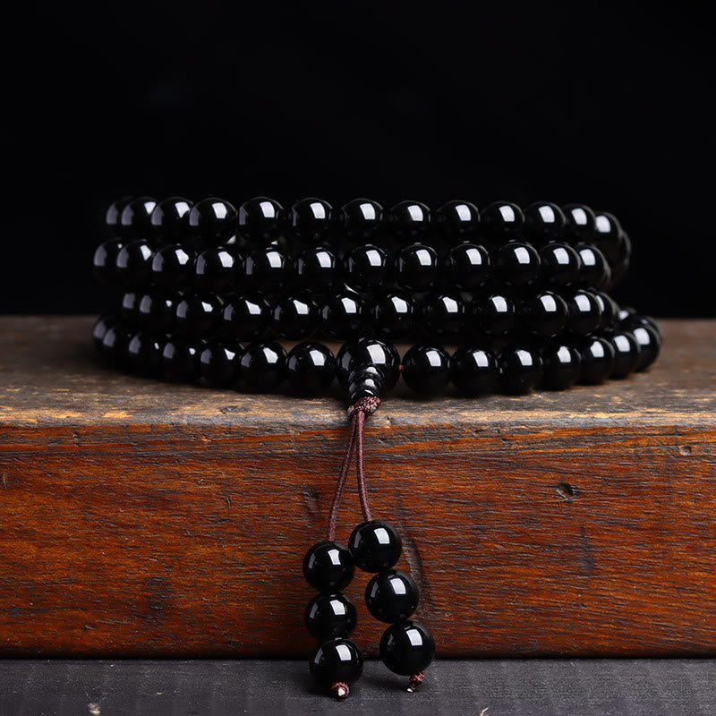 Black beaded necklace on a wooden surface with a dark background
