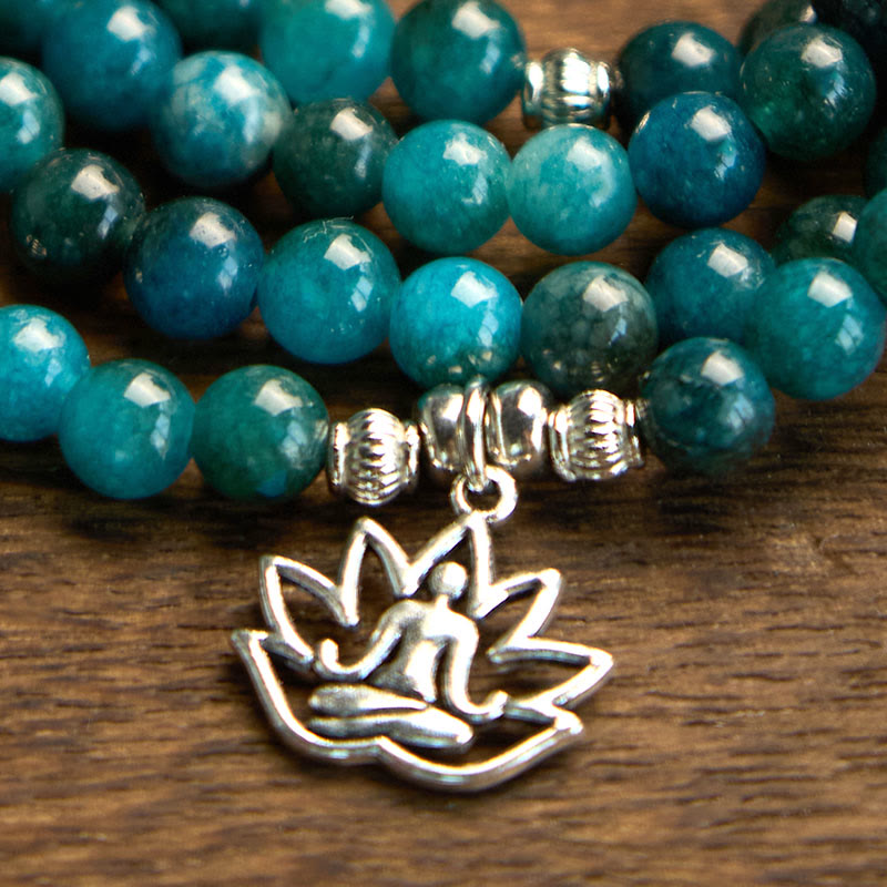 Teal beaded bracelet with silver lotus flower charm on a wooden surface