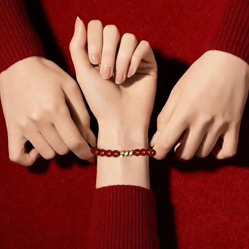 Close-up of a hand wearing a red beaded bracelet against a red background