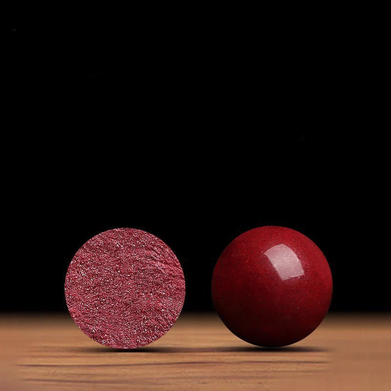 Two red objects, one smooth and one textured, on a wooden surface with a black background.