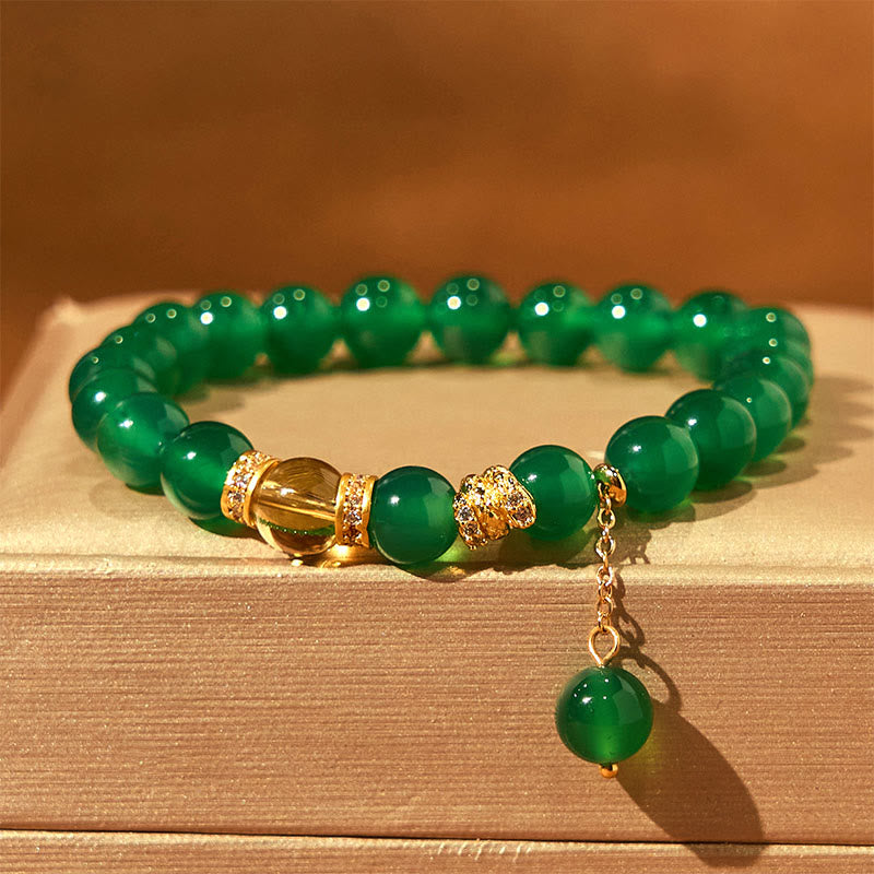 Green beaded bracelet with gold accents on a wooden surface