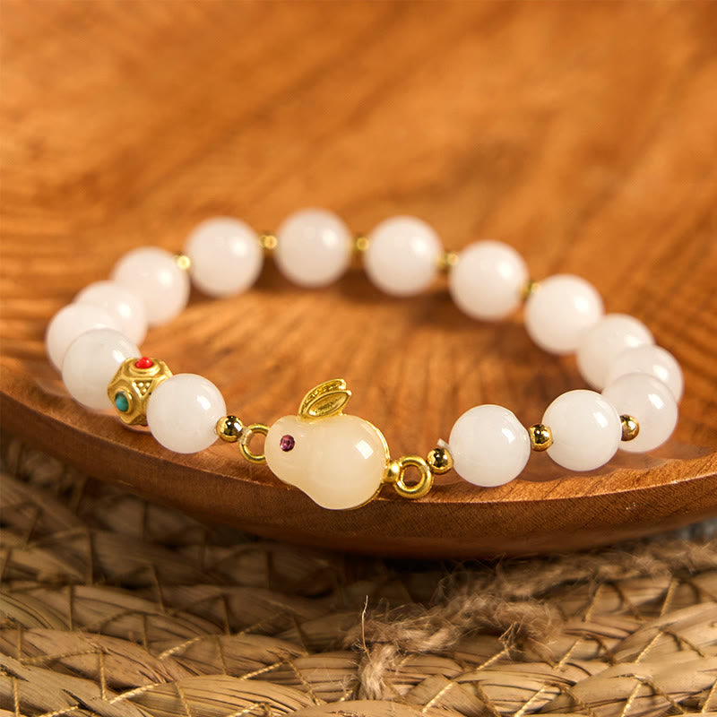 White beaded bracelet with gold accents on a wooden surface
