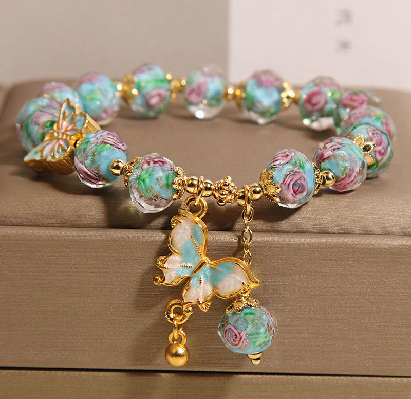 Bracelet with floral beads and butterfly charms on a wooden surface