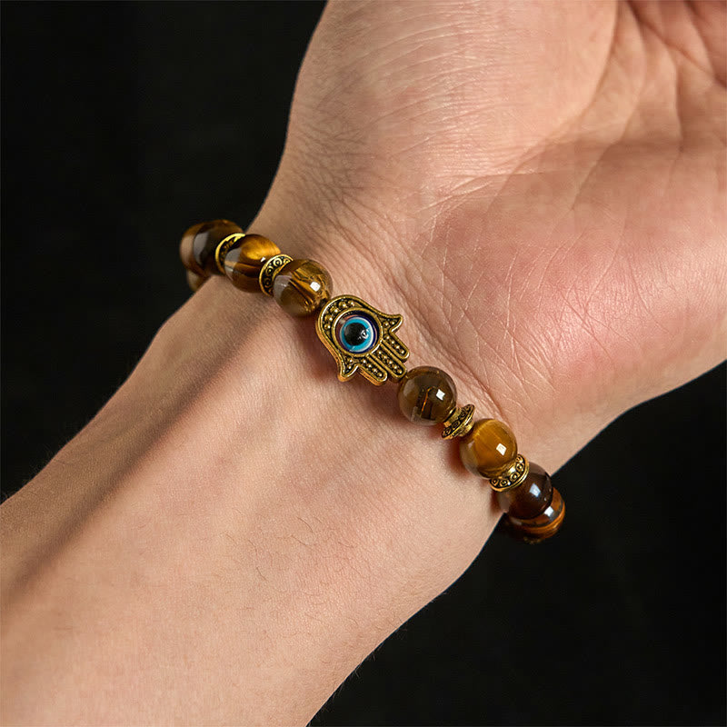 Bracelet with beaded design and Hamsa hand charm on wrist against a dark background