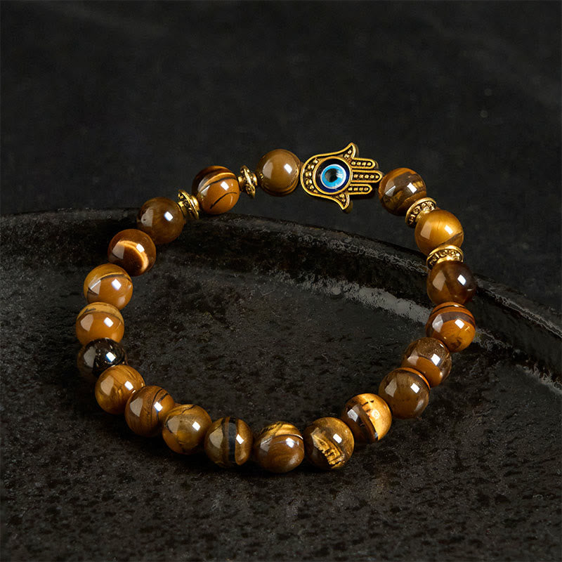 Beaded bracelet with a Hamsa hand charm on a dark surface