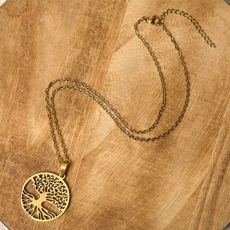 Gold necklace with a tree of life pendant on a wooden surface