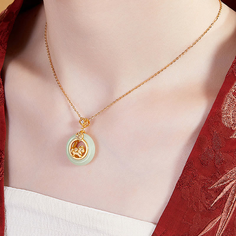 Gold necklace with a green pendant on a person wearing a red and white outfit.