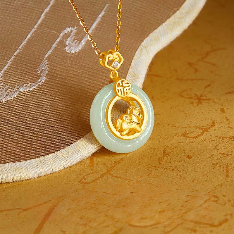 Gold and jade pendant necklace on a textured fabric background