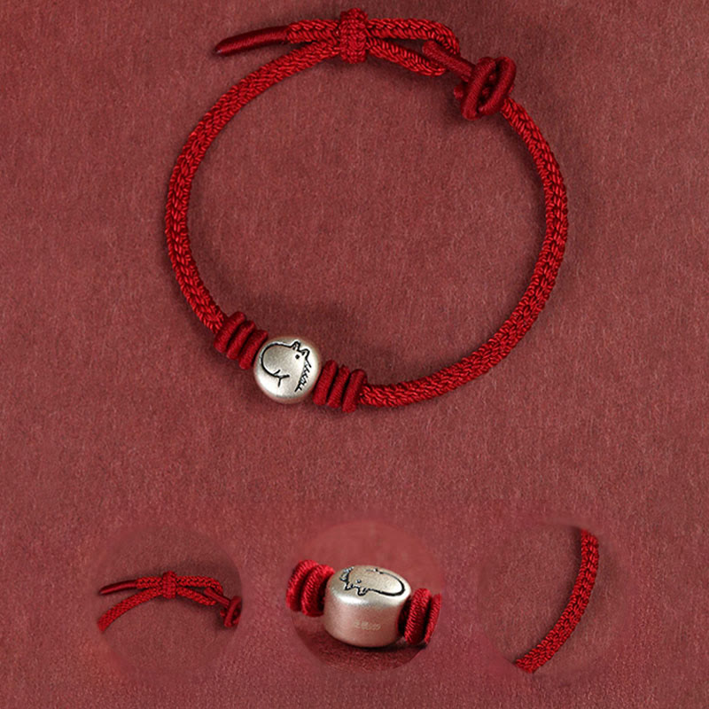 Red bracelet with a silver charm on a red background