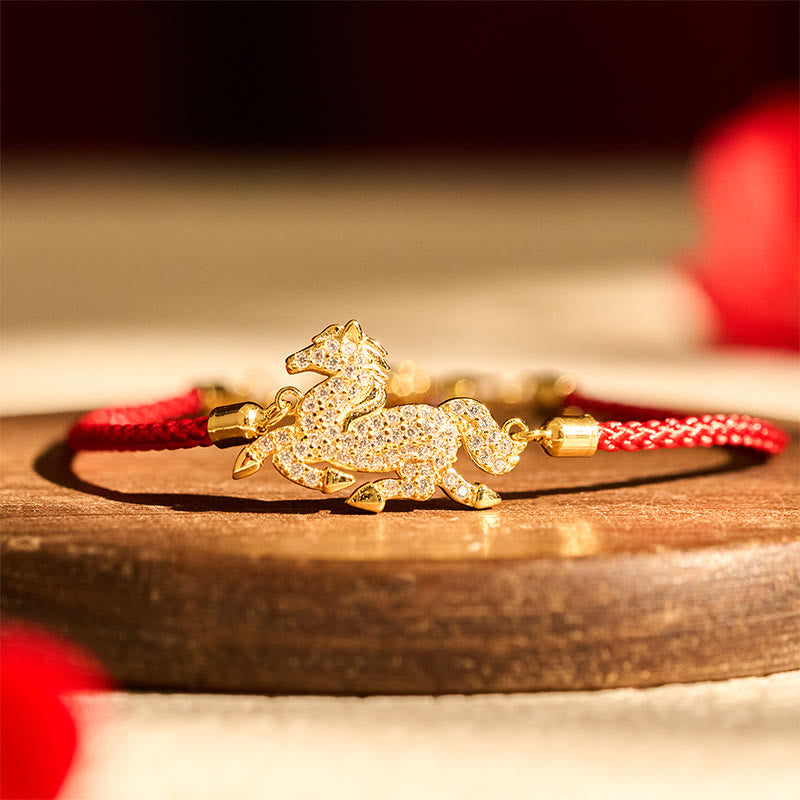 Gold bracelet with a horse charm on a wooden surface