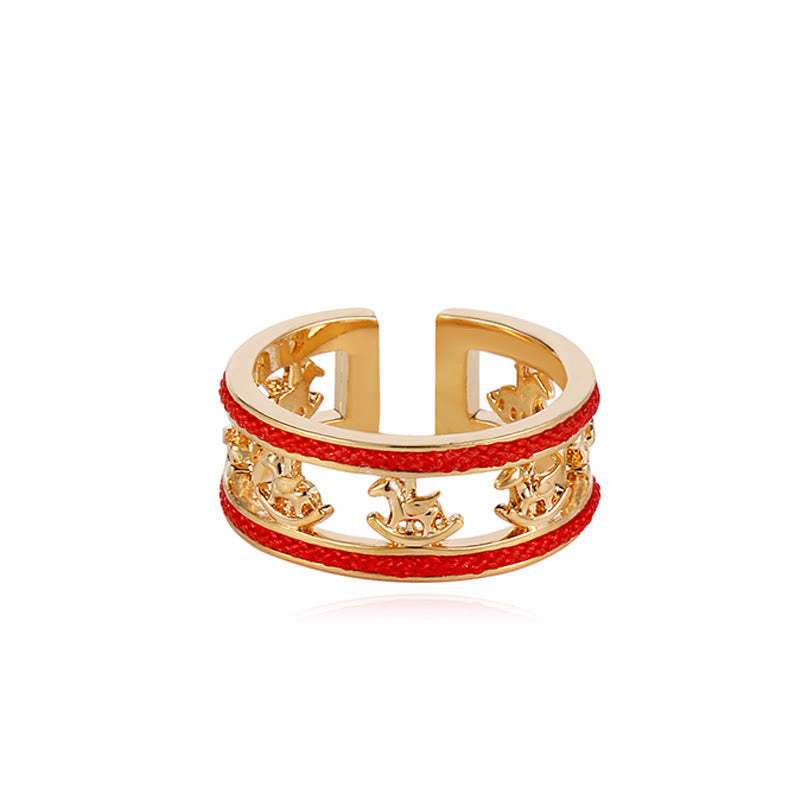 Gold ring with red band featuring zodiac symbols on a white background