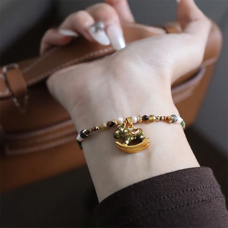 Gold bracelet with a heart charm on a wrist against a blurred background