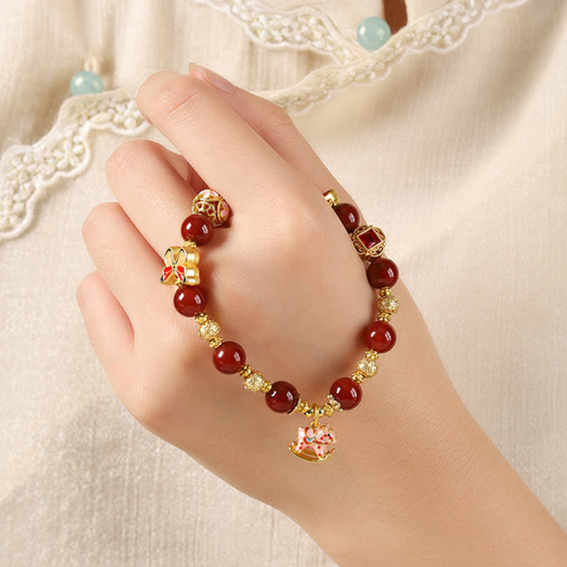 Hand wearing a red beaded bracelet with gold accents on a light background