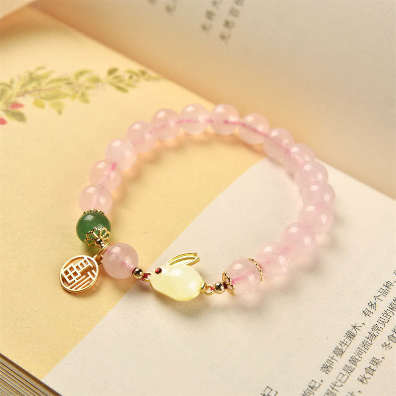 Pink beaded bracelet with a yellow charm on a book
