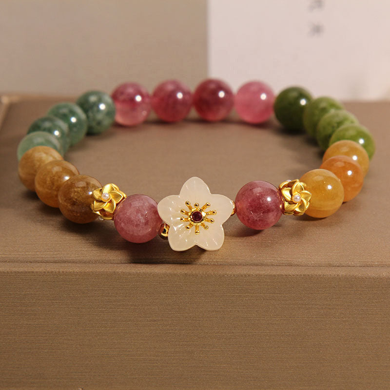 Multicolored beaded bracelet with a decorative flower clasp on a brown surface