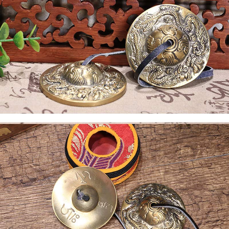 Two brass gongs with intricate designs on a wooden surface.