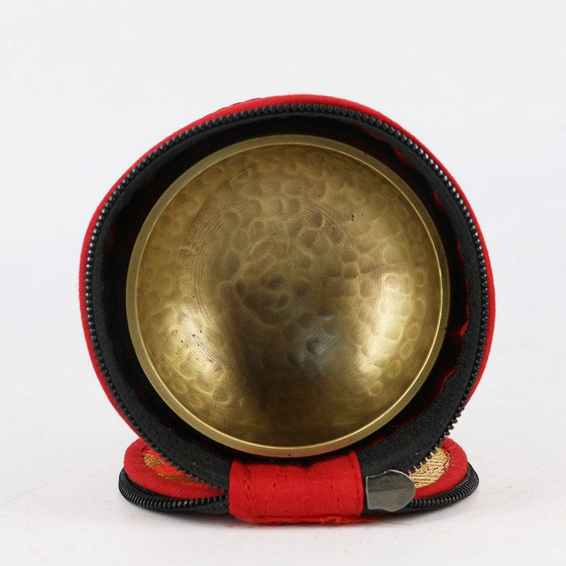 Brass singing bowl in a red and black carrying case on a white background