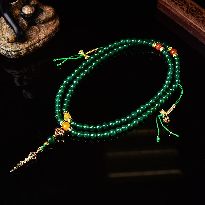 Green beaded necklace with decorative elements on a dark background