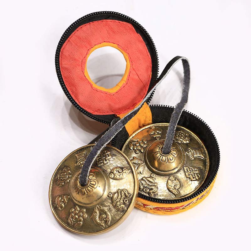 Pair of brass hand chimes in a black and orange case on a white background