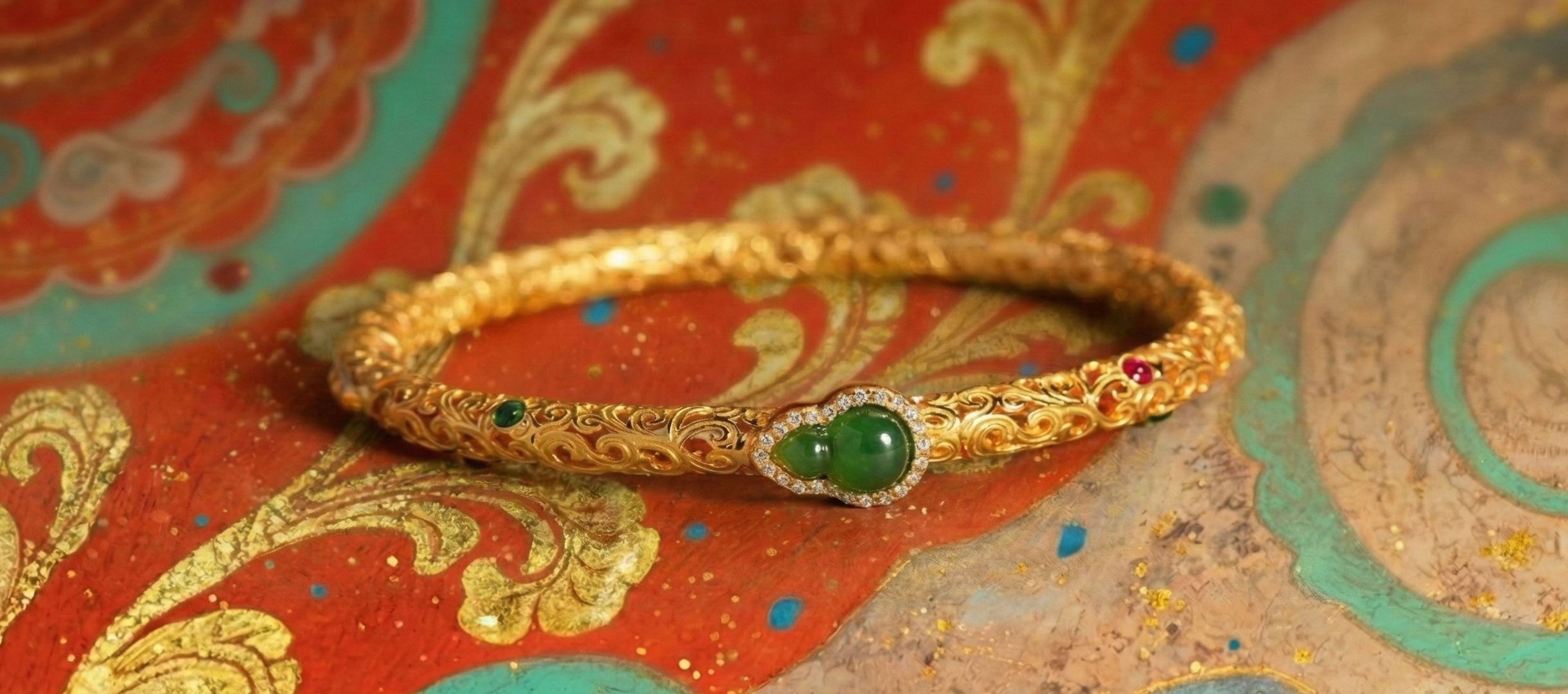 Gold bracelet with green gemstones on a decorative red and gold background