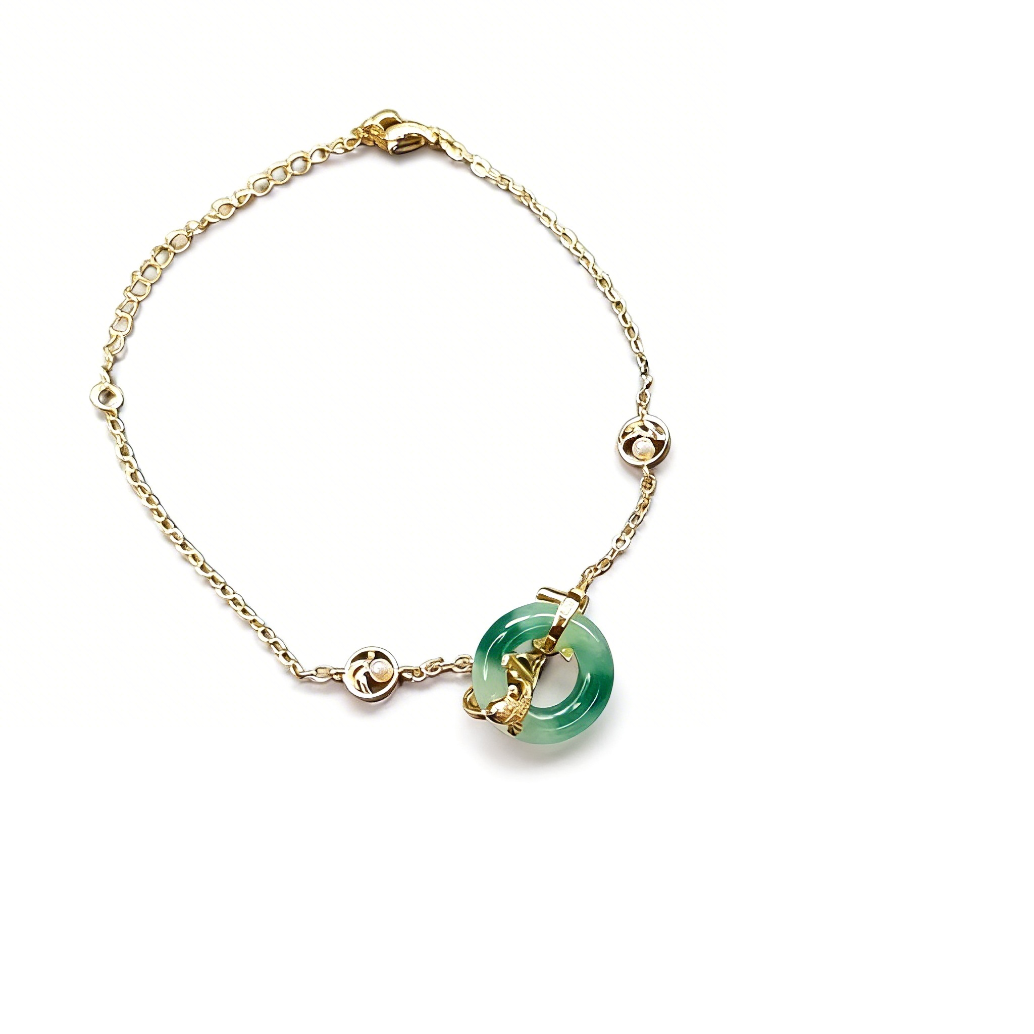 Gold bracelet with a green gemstone on a white background