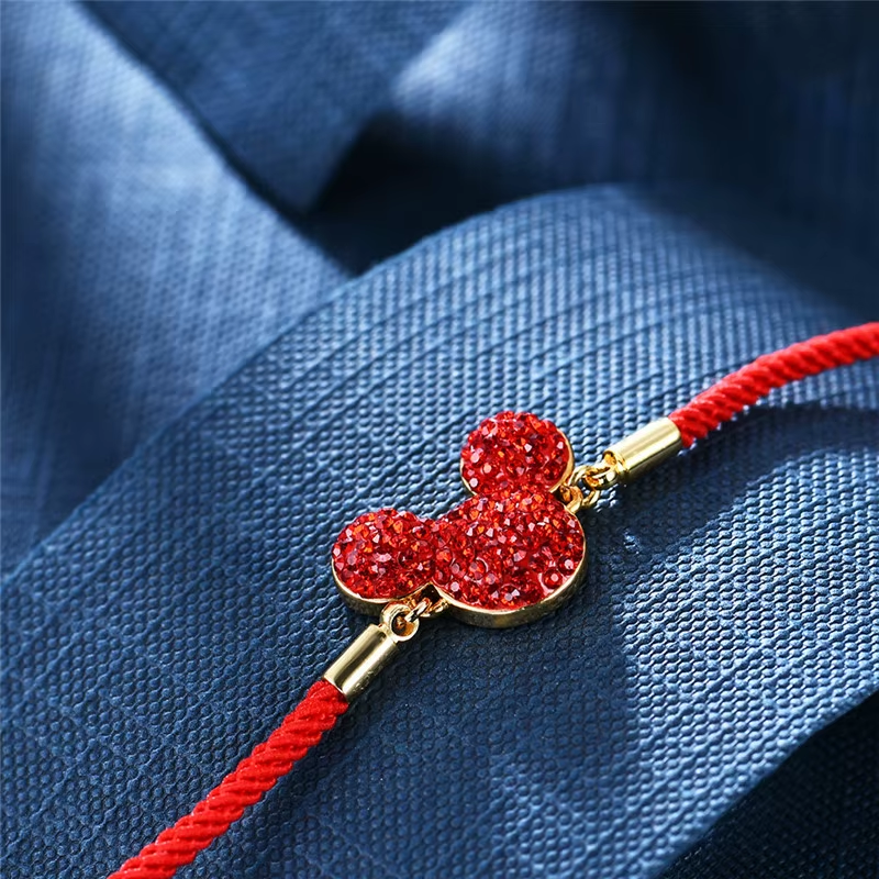 Bracelet with red and gold charm on a blue fabric background
