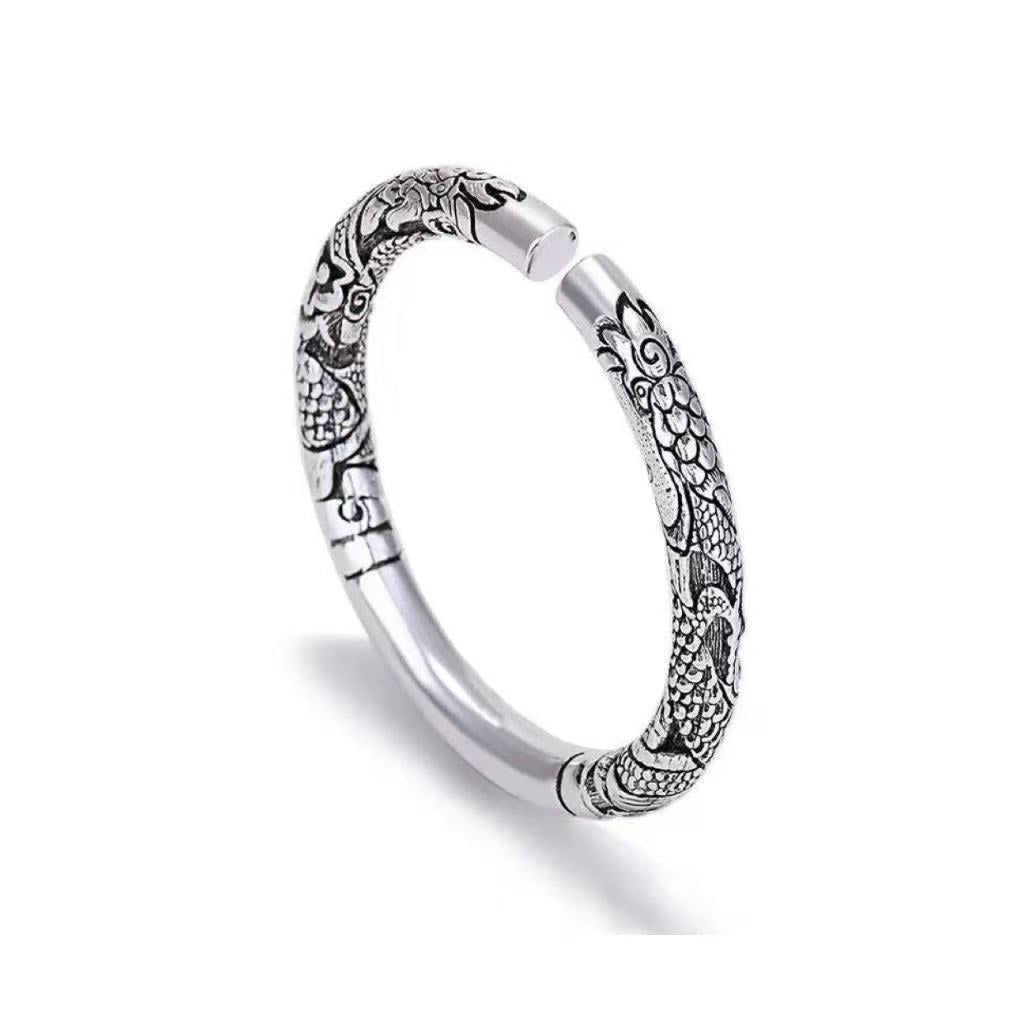 Silver ring with intricate designs on a white background