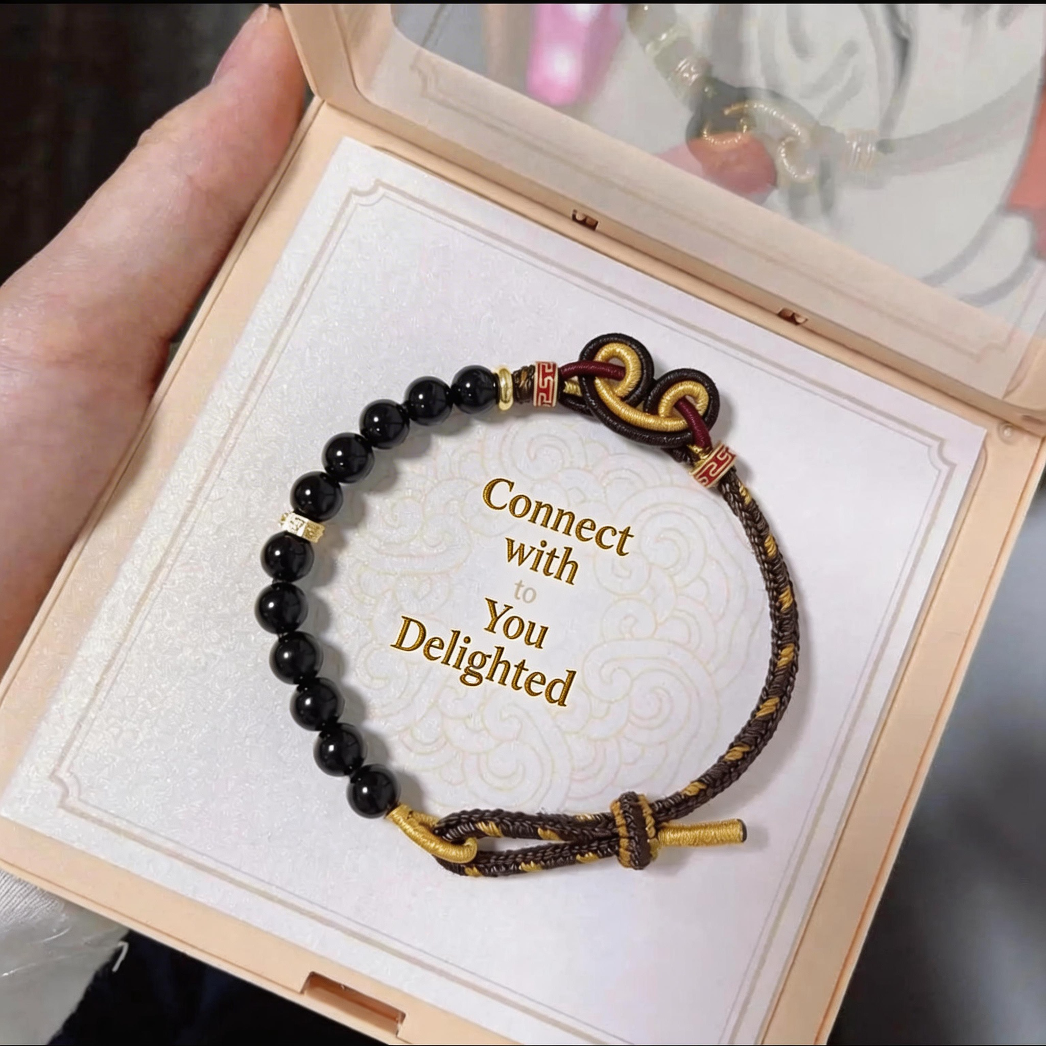 Black beaded bracelet with gold accents in a wooden box, featuring the text 'Connect with You Delighted'.