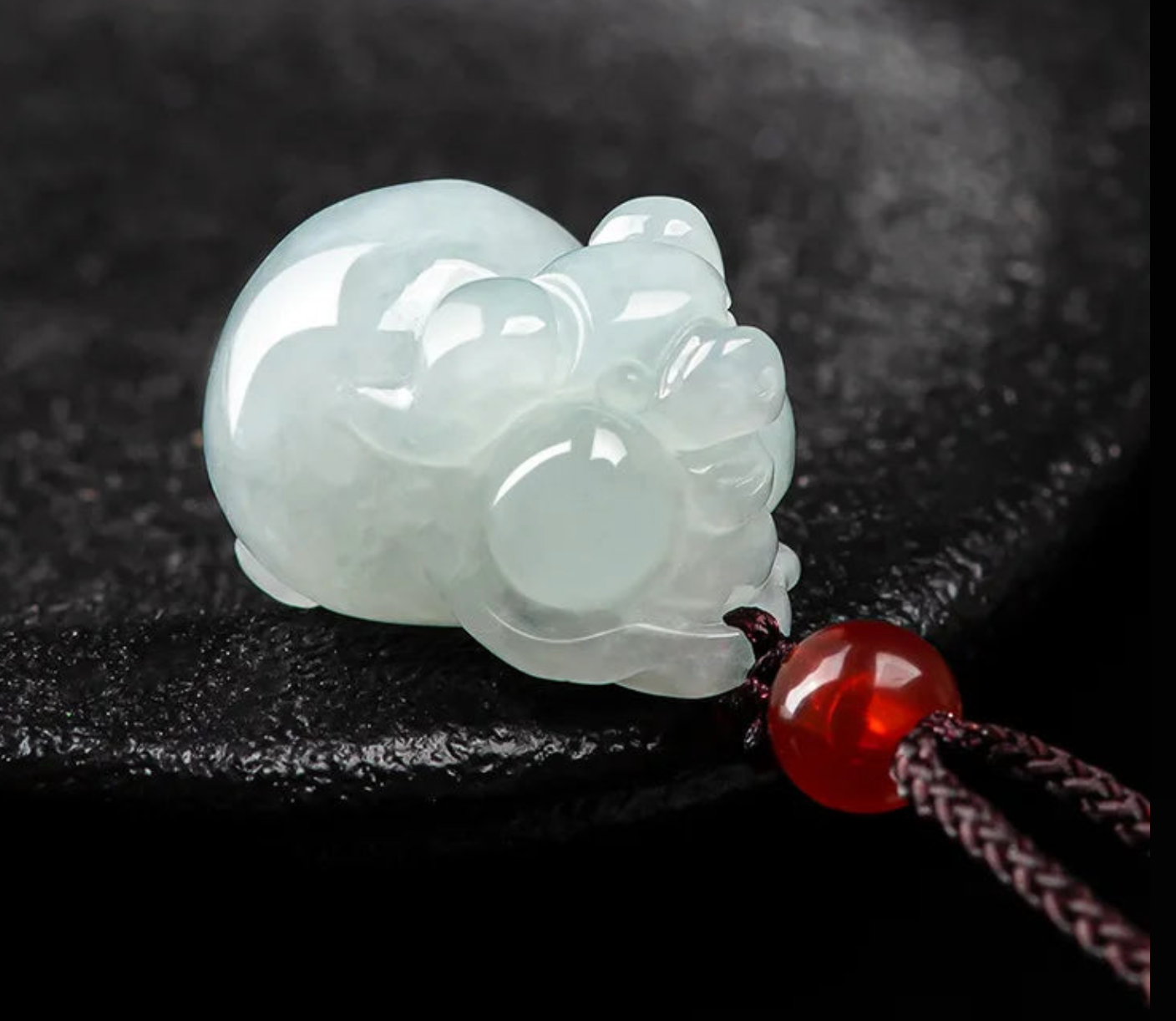 White jade pendant shaped like a cat on a dark background