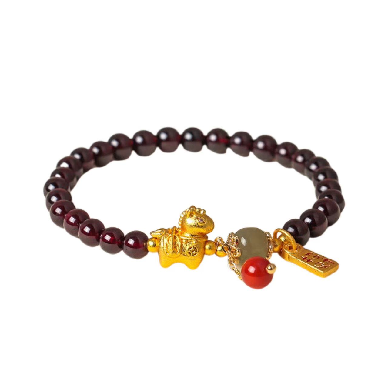 Bracelet with dark beads and gold and red charms on a white background