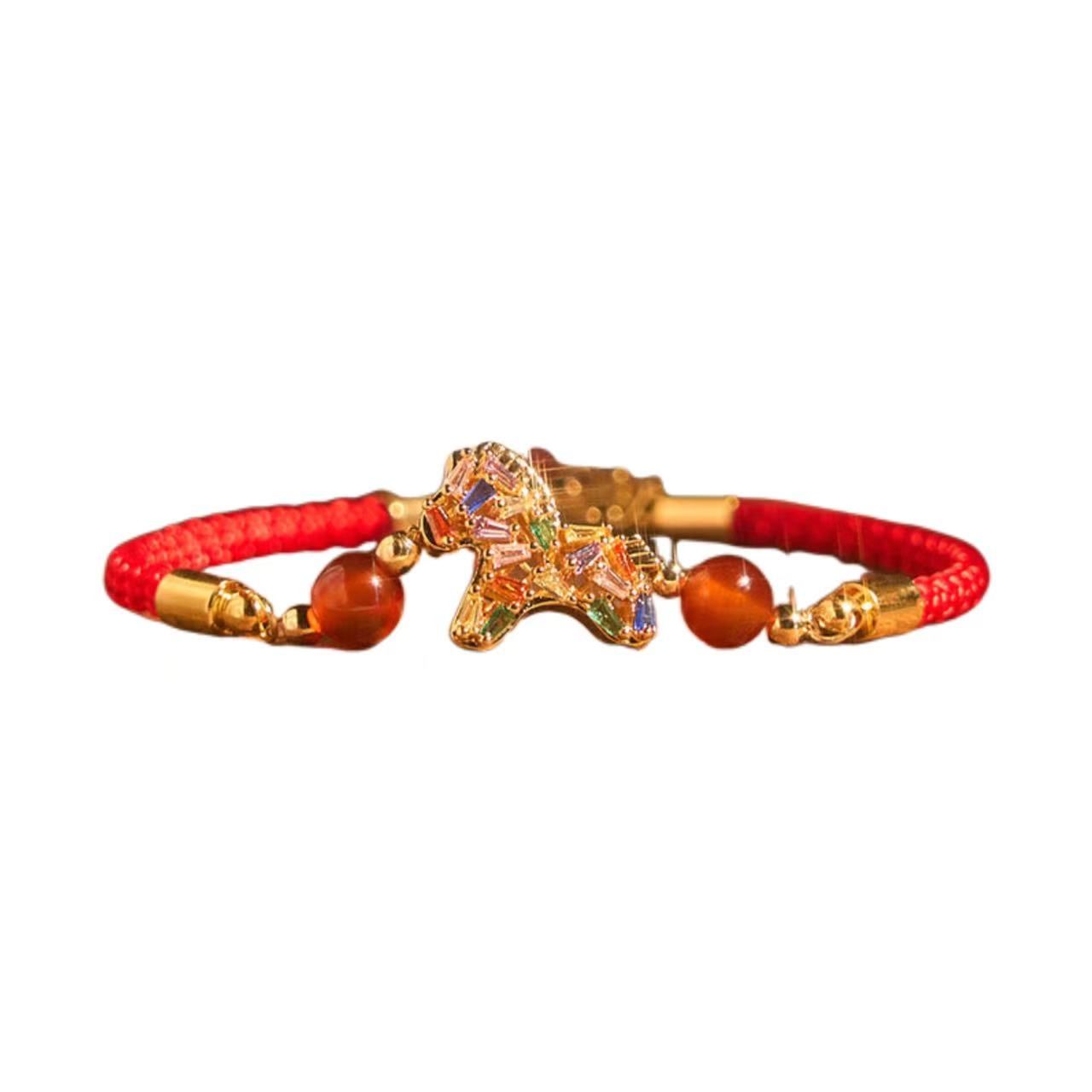 Bracelet with red cord, gold clasp, and decorative elements on a white background