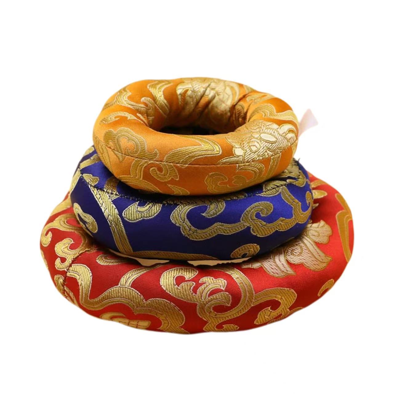 Three decorative pillows stacked on top of each other with gold, blue, and red colors.
