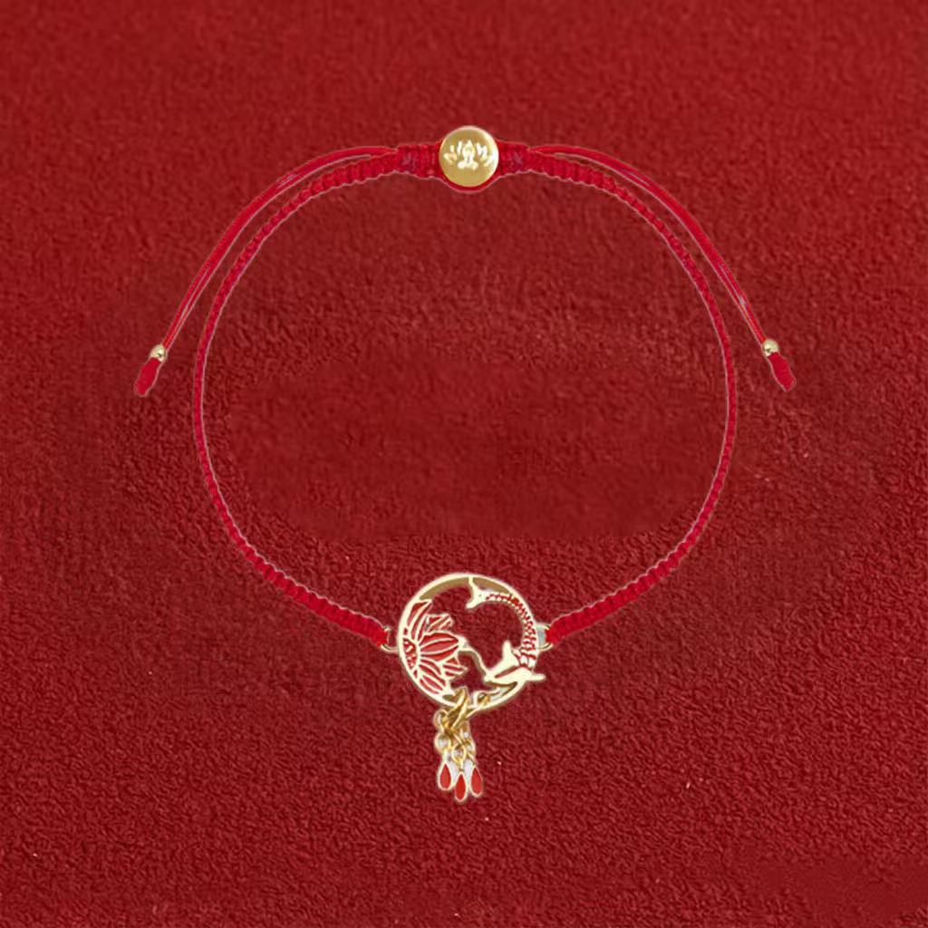 Red cord bracelet with gold charm on a red background