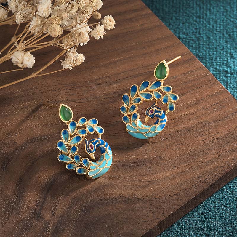 Pair of decorative earrings on a wooden surface with dried flowers.