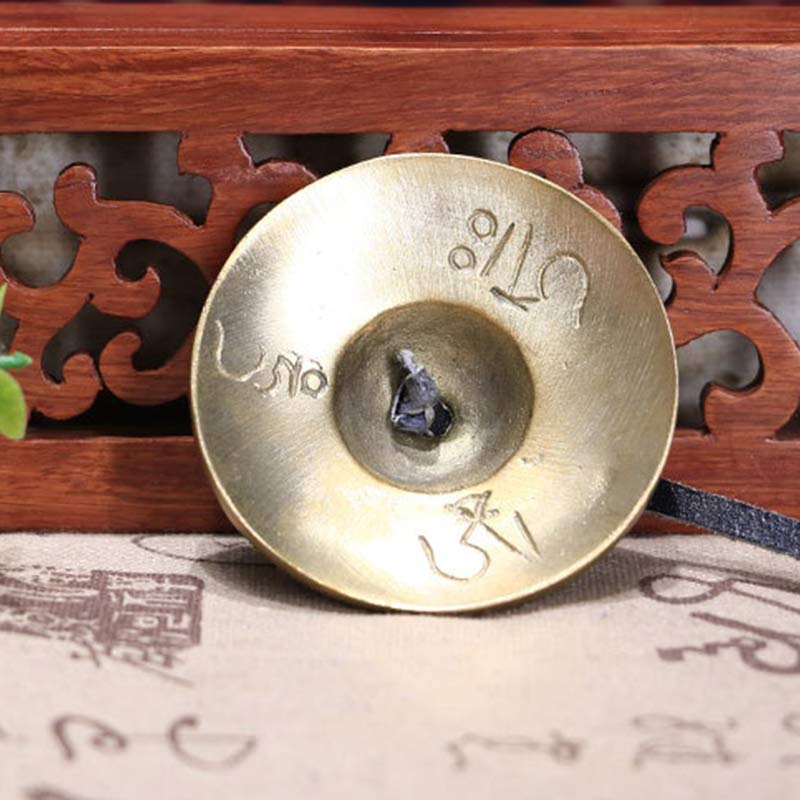 Brass cymbal with engraved text on a wooden background