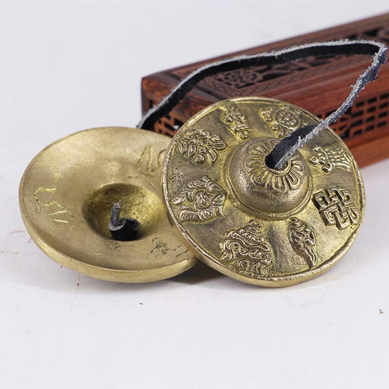 Pair of brass chimes with intricate designs on a white background