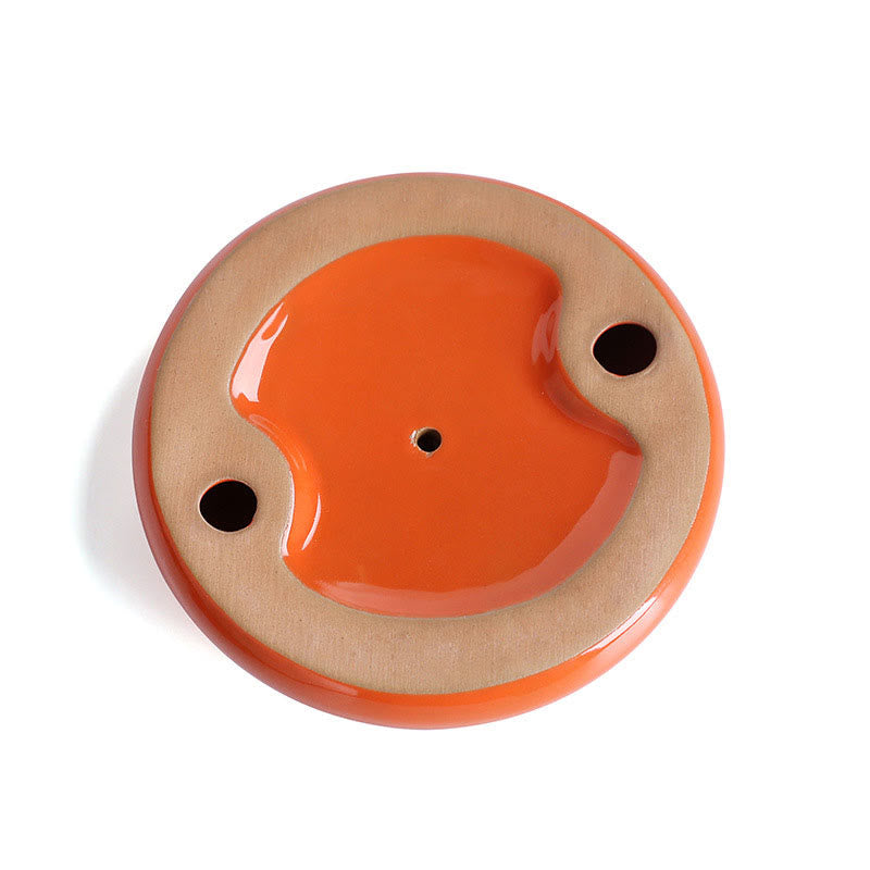 Ceramic dish with orange center and beige rim on a white background