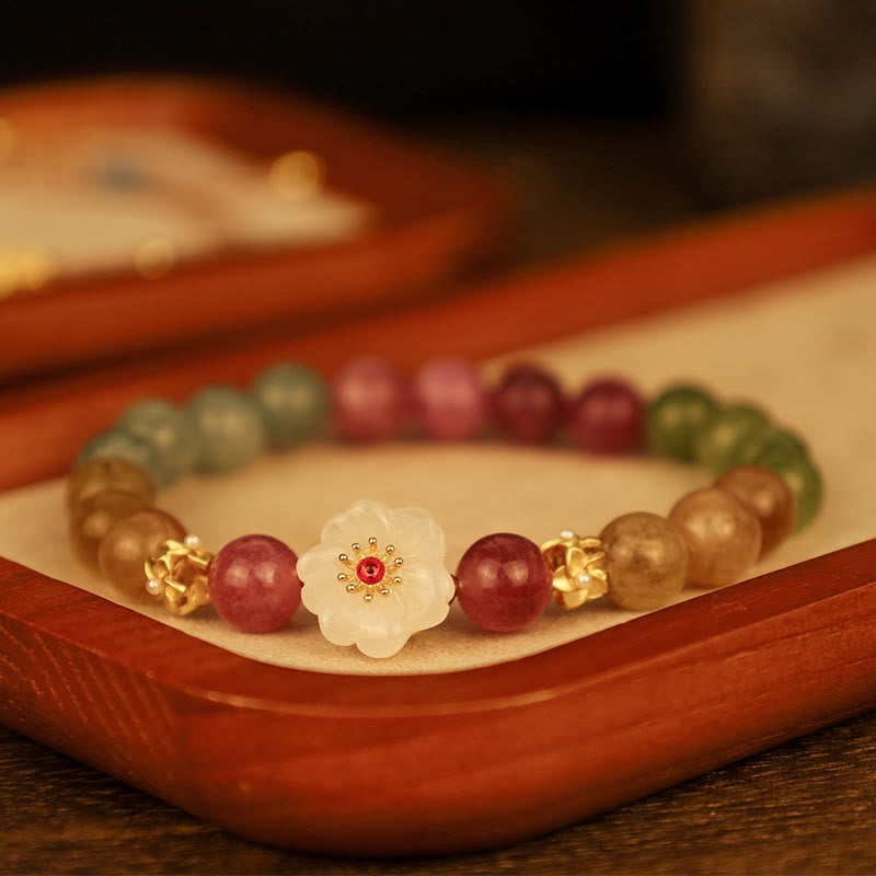 Colorful beaded bracelet with a decorative flower charm on a wooden tray.