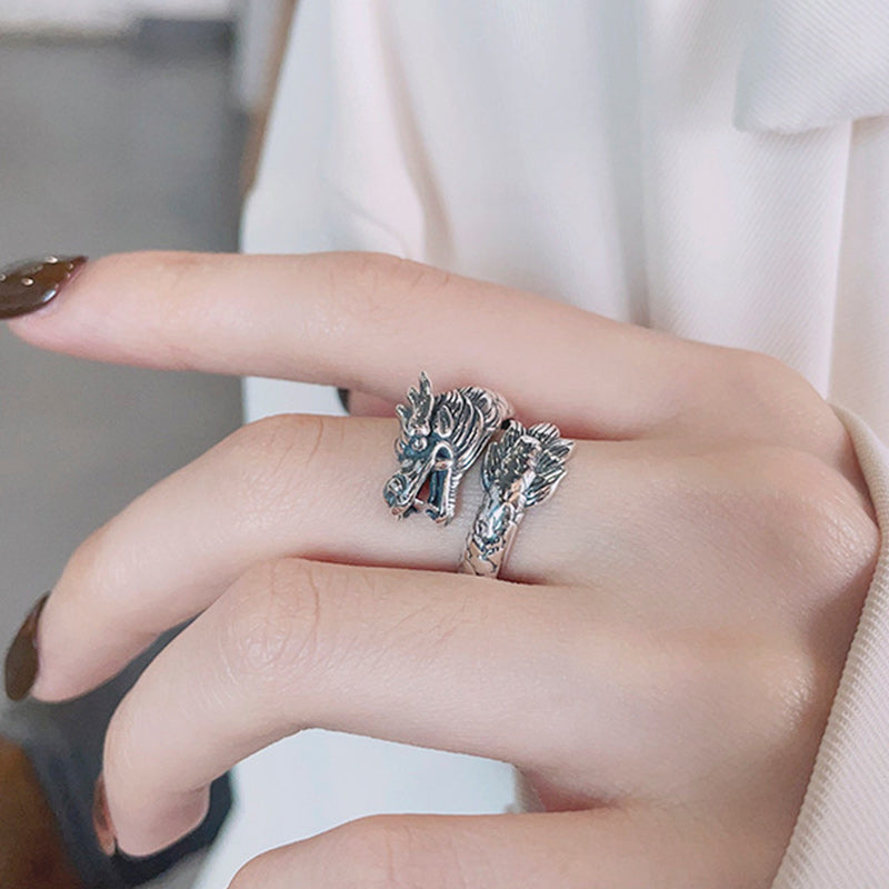 Silver ring with horse design on a finger against a neutral background