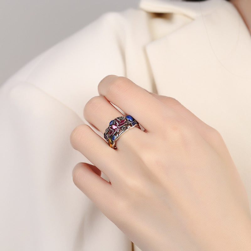 Hand wearing a colorful ring on a neutral background
