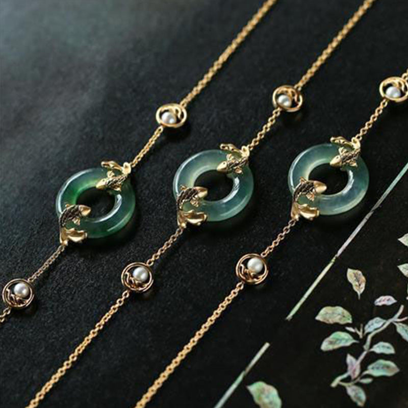 Three green jade necklaces with gold chains on a dark background