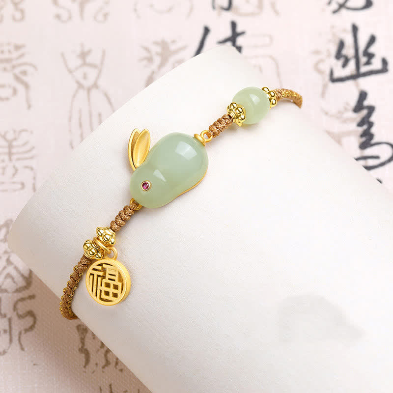 Gold and jade bracelet on a white surface with Chinese characters in the background