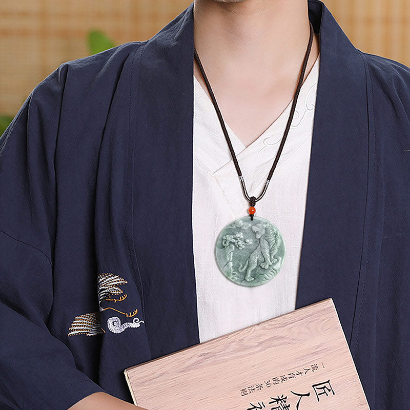 Person wearing a dark blue traditional outfit with a green jade pendant and holding a wooden box.