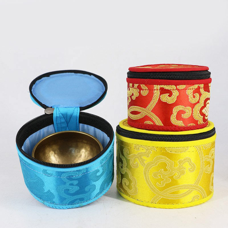 Three fabric containers with gold patterns, one open showing a brass bowl, on a white background.